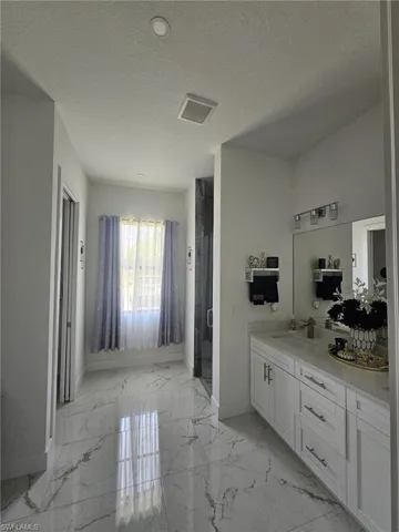 Full bathroom featuring baseboards, marble finish flooring, vanity, a textured ceiling, and a shower stall