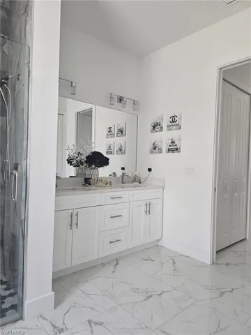 Full bathroom with marble look tiles, baseboards, and a stall shower
