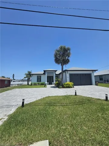 View of front of property featuring decorative driveway, a front yard, an attached garage, and stucco siding