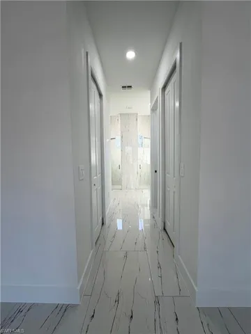 Hallway with recessed lighting and light marble finish flooring