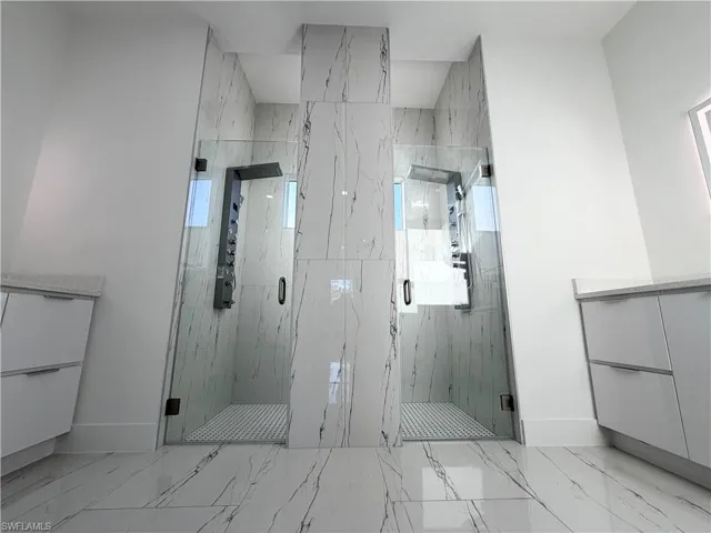 Bathroom with vanity, a marble finish shower, and light marble finish flooring