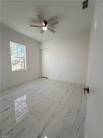 Empty room with light marble finish flooring and a ceiling fan