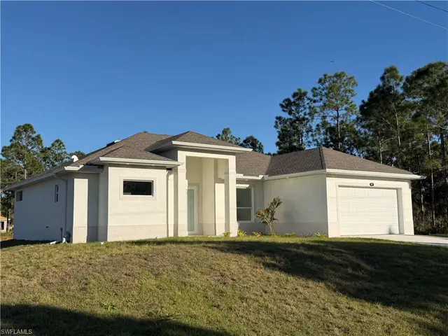 View of front of property featuring a garage, a front yard, and stucco siding