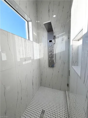 Full bath featuring a marble finish shower