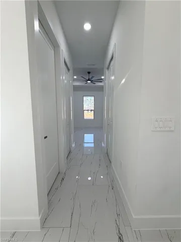 Hall featuring recessed lighting and light marble finish flooring