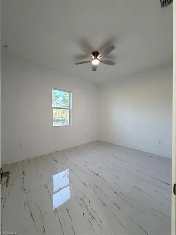 Spare room featuring light marble finish floors and a ceiling fan