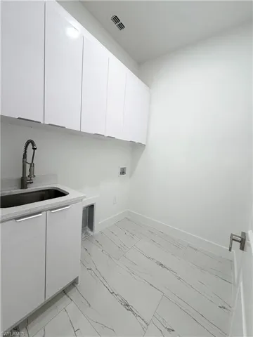 Laundry room featuring cabinet space, light marble finish floors, and hookup for a washing machine