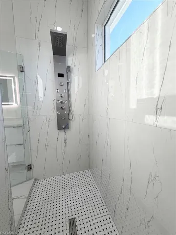Full bath with a marble finish shower