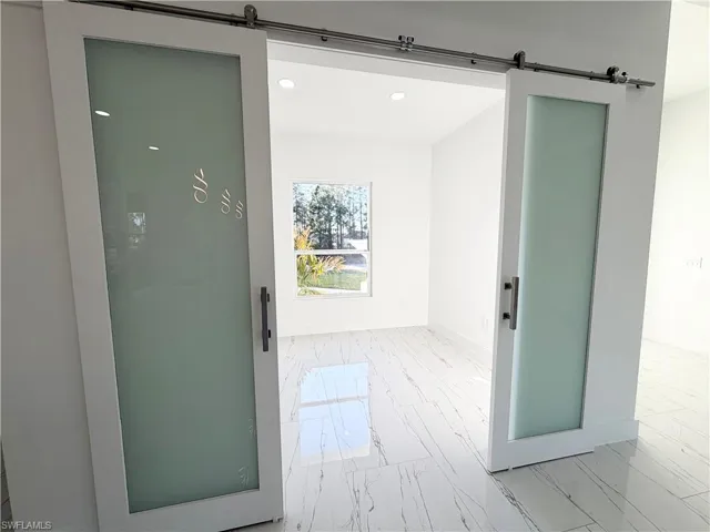 Doorway to outside featuring a barn door, recessed lighting, and marble finish flooring