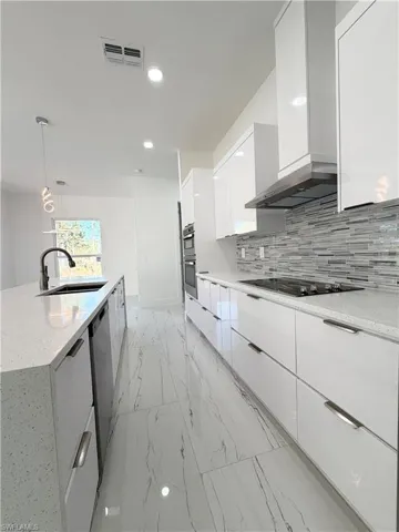 Kitchen featuring modern cabinets, light stone counters, white cabinetry, and light marble finish floors