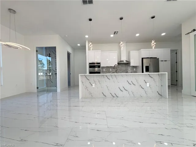 Kitchen with hanging light fixtures, white cabinets, modern cabinets, and stainless steel appliances