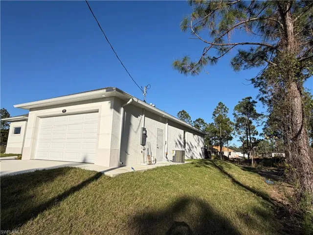 View of home's exterior with a yard, stucco siding, a garage, and driveway