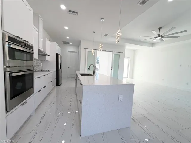 Kitchen featuring a barn door, stainless steel appliances, white cabinetry, and modern cabinets