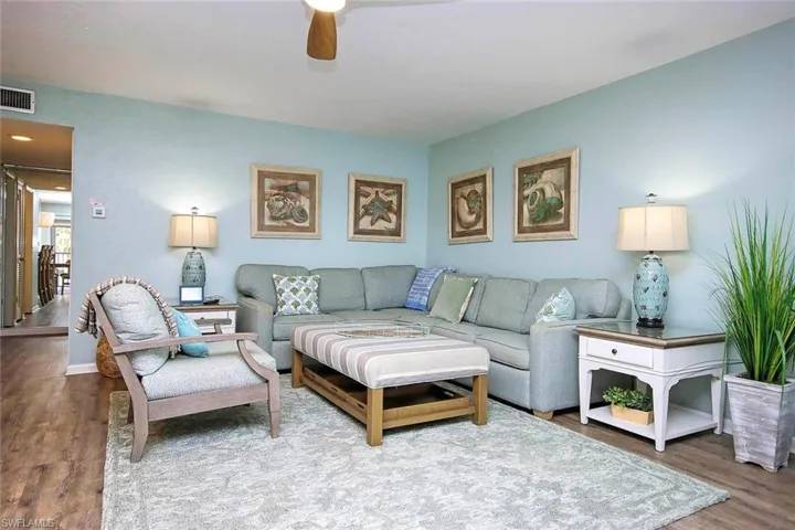 Living room with wood finished floors, a ceiling fan, visible vents, and baseboards