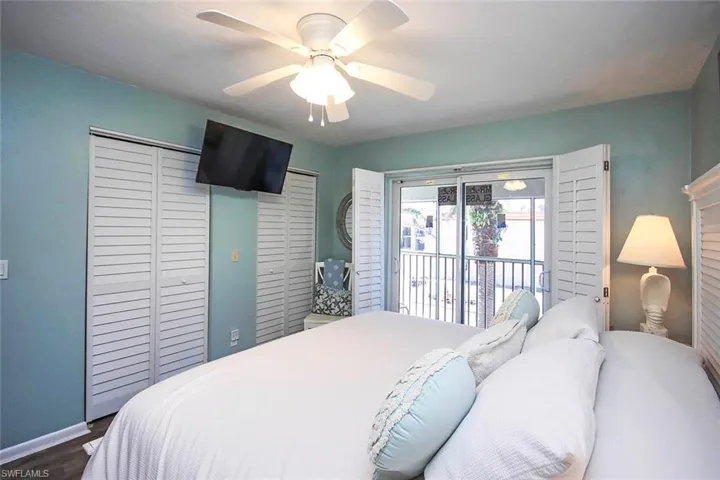 Bedroom featuring access to exterior, dark wood-style floors, baseboards, and ceiling fan