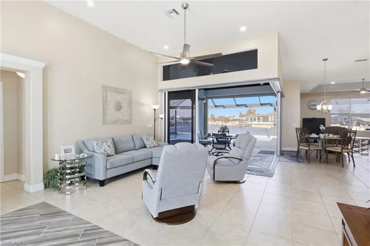 Soaring vaulted ceilings and expansive glass doors fill this living space with natural light and captivating water views.