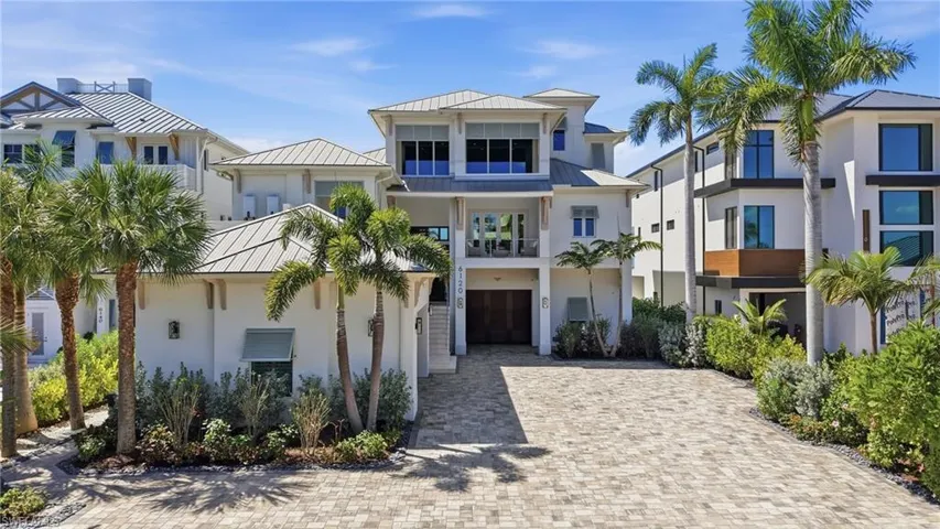 View of front of property featuring a standing seam roof, a garage, a balcony, and driveway - Virtually Edited Image