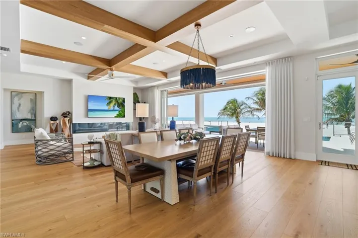 Dining area featuring light wood-style floors, coffered ceiling, ceiling fan, and recessed lighting - Virtually Edited Image