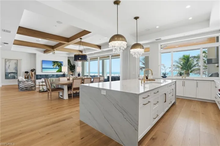 Kitchen featuring light stone countertops, light wood-style floors, a large island, open floor plan, and coffered ceiling - Virtually Edited Image