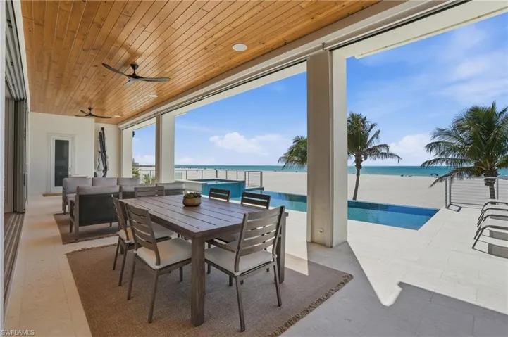 View of patio / terrace with ceiling fan, an outdoor pool, outdoor dining space, and a water view - Virtually Edited Image
