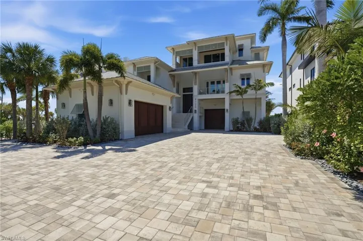 Coastal home featuring driveway, stucco siding, and an attached garage - Virtually Edited Image