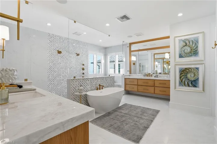 Bathroom featuring a walk in shower, two vanities, a soaking tub, and tile walls - Virtually Edited Image