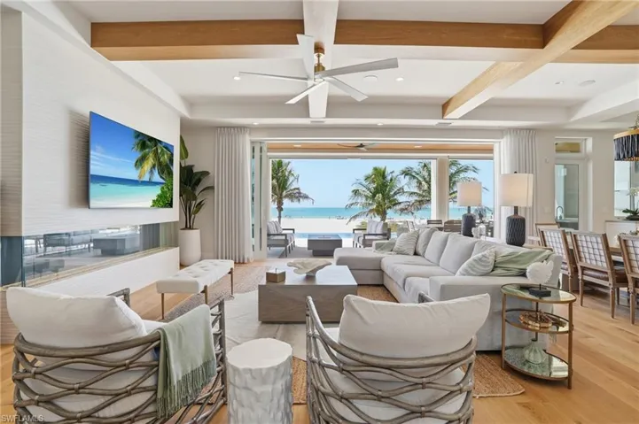 Living room featuring a ceiling fan, light wood-style flooring, plenty of natural light, coffered ceiling, and recessed lighting - Virtually Edited Image
