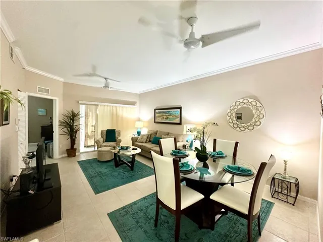 Dining space featuring light tile patterned floors, ceiling fan, and crown molding