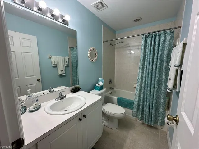 Full bathroom with shower / tub combo with curtain, vanity, tile patterned floors, and toilet