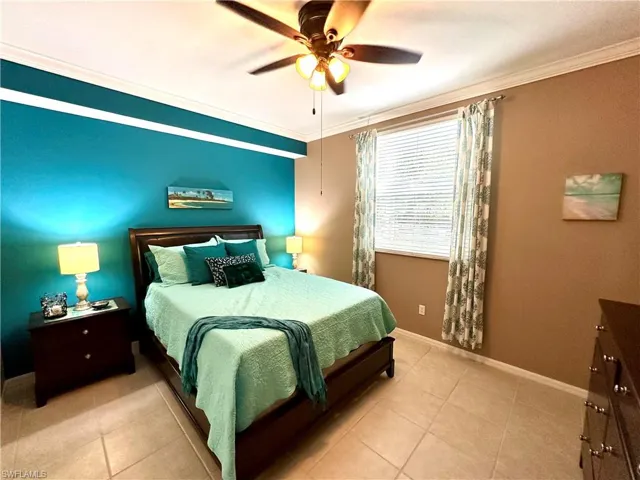 Bedroom with ceiling fan, tile patterned flooring, and crown molding