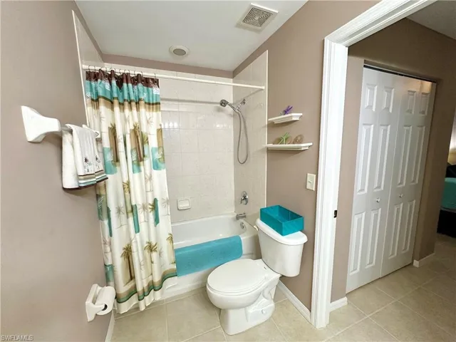 Bathroom featuring shower / tub combo, tile patterned flooring, and toilet