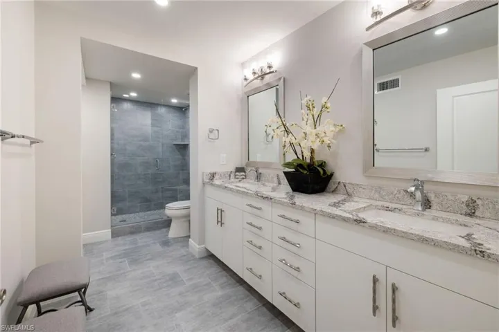 Beautifully remodeled primary bathroom featuring a modern walk-in shower with designer tile, dual sinks, and sleek contemporary vanity