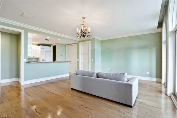 Living area with a chandelier, light wood-style flooring, baseboards, crown molding, and recessed lighting