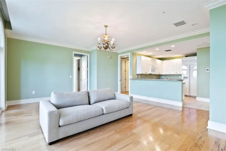 Living area featuring a chandelier, light wood-type flooring, baseboards, ornamental molding, and recessed lighting