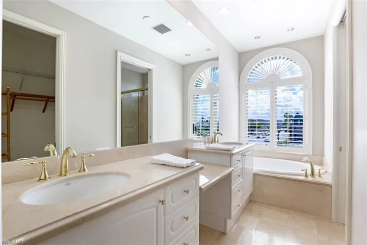 Full bathroom featuring a shower stall, a garden tub, vanity, tile patterned flooring, and a walk in closet