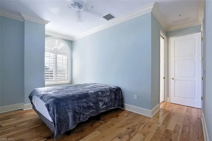 Bedroom with wood finished floors, ornamental molding, and baseboards
