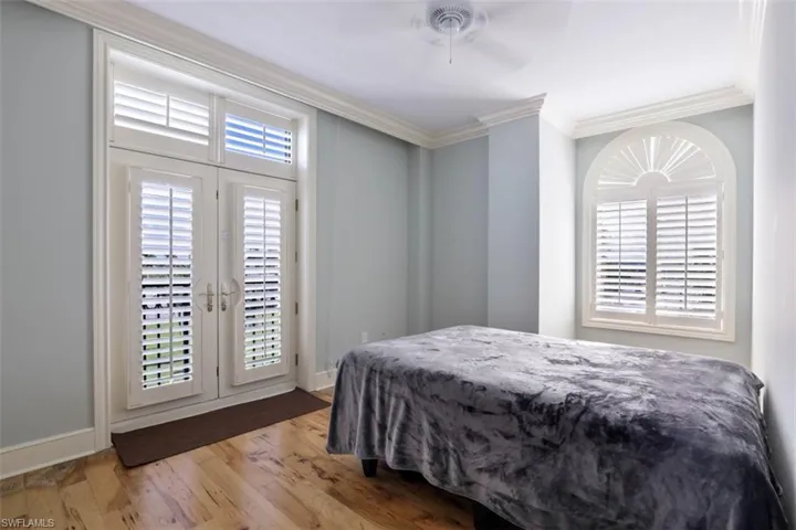 Bedroom with crown molding, wood finished floors, baseboards, ceiling fan, and access to exterior