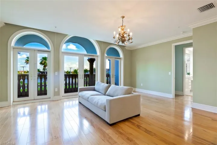 Living room featuring a chandelier, light wood-style flooring, baseboards, french doors, and ornamental molding