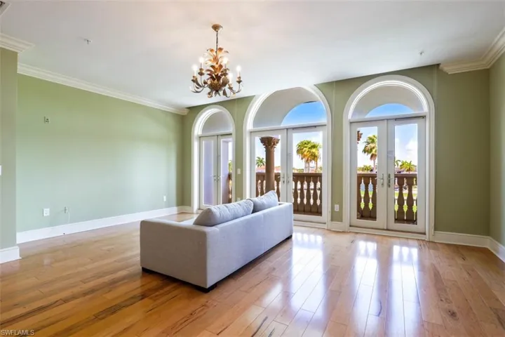 Living room featuring french doors, a chandelier, crown molding, baseboards, and light wood-style floors