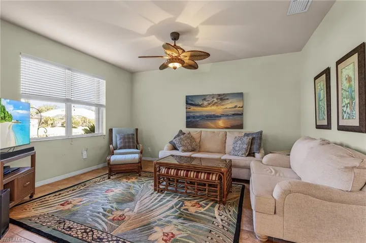 Living room with a ceiling fan and light tile patterned flooring