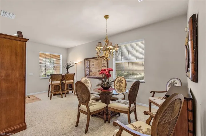 Dining space featuring light colored carpet and a chandelier