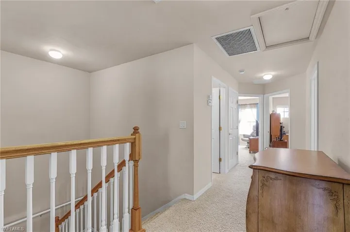 Hallway featuring an upstairs landing and light colored carpet