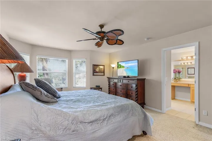 Bedroom featuring light carpet, ceiling fan, and ensuite bathroom