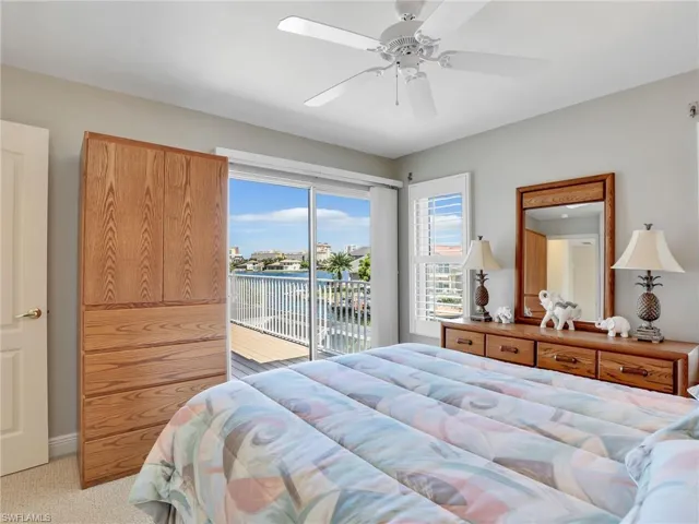 Bedroom featuring access to outside, a water view, light colored carpet, and ceiling fan