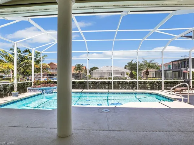 Swimming pool featuring a sunroom, glass enclosure, a patio, and a residential view