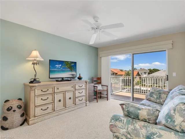 Living room featuring carpet floors, a ceiling fan, and a residential view