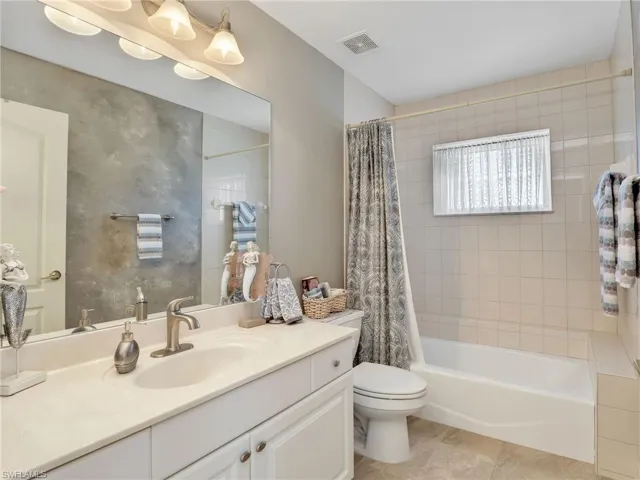 Bathroom featuring shower / tub combo, vanity, and light tile patterned flooring