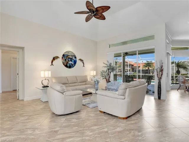Living room with a high ceiling, a sunroom, and ceiling fan