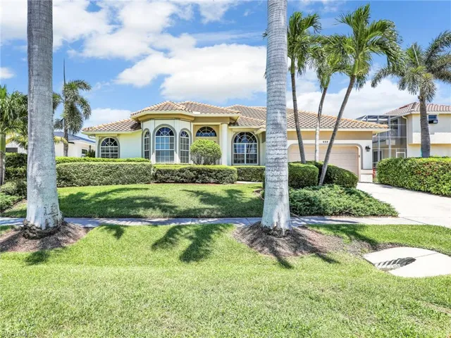 View of front of property featuring stucco siding, an attached garage, a front lawn, driveway, and a tile roof
