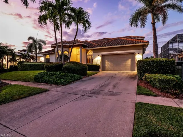 Mediterranean / spanish house with stucco siding, a tile roof, driveway, a garage, and a front lawn